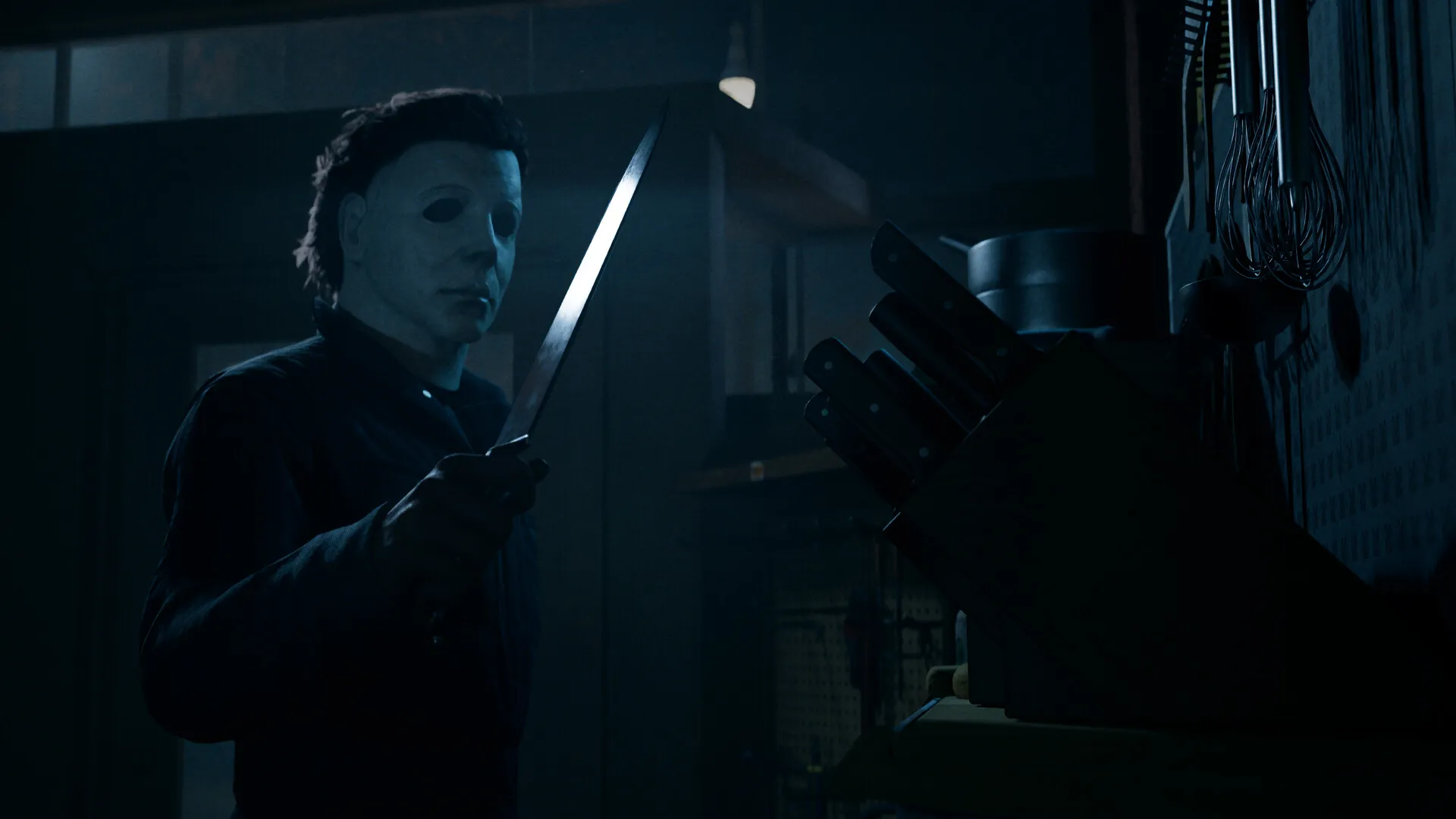 Halloween: The Game : Michael Myers, couteau à la main, dans une pièce faiblement éclairée d'une maison de Haddonfield : visuel officiel